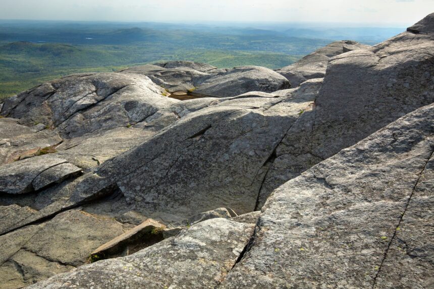 shutterstock 2024657870 glacially sculpted granite bedrock green valley and mountains in distance