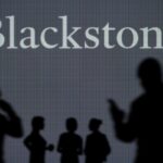 The Blackstone logo is seen on an LED screen in the background while a silhouetted person uses a smartphone in the foreground.