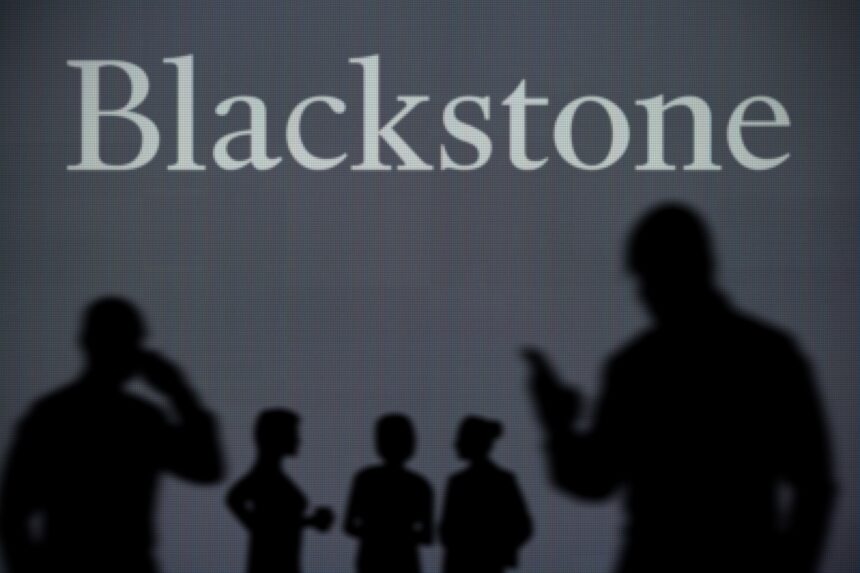 The Blackstone logo is seen on an LED screen in the background while a silhouetted person uses a smartphone in the foreground.