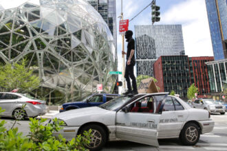 Protesters block traffic as they participate in a "car caravan" protest at the Amazon Spheres to demand the Seattle City Council tax the city