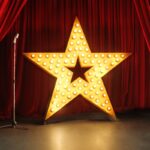 shutterstock 218547988 retro stage with red curtains standing mic and giant gold star with lights