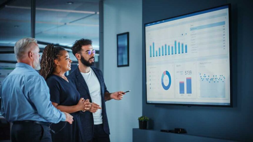 Company Operations Manager Holds Meeting Presentation. Diverse Team Uses TV Screen with Growth Analysis, Charts, Statistics and Data. People Work in Business Office.