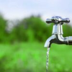 shutterstock 434035804 water flowing from a silver outdoor tap amid green fields and green trees