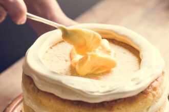 shutterstock 1104796700 layer cake with white and yellow frosting on a wooden table