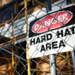 shutterstock 77002051 Danger hard hat area safety warning sign chain link fence construction site