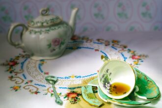 dropped  china cup of tea on a broken saucer with spilled tea on table cloth