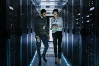 Male and Female Server Technicians Working in Data Center. Running Rack Server Diagnostics. Woman Uses Tablet Computer.