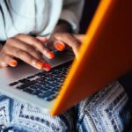 Hands type on a laptop keyboard.