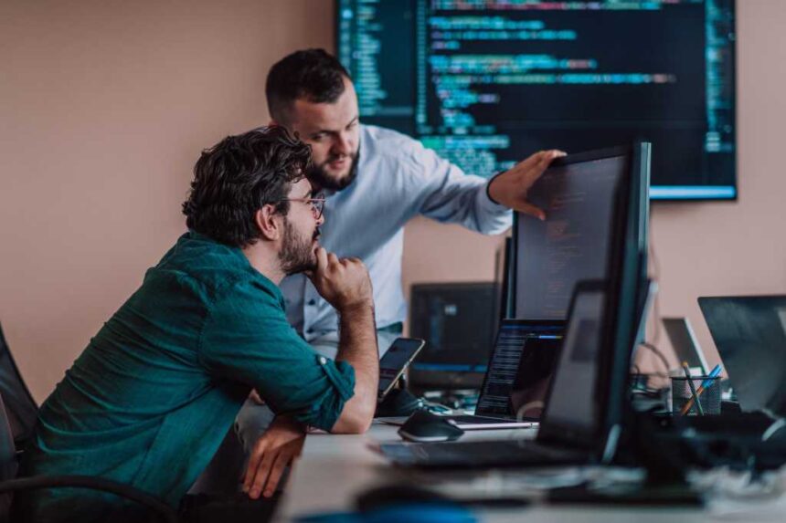 Programmers engrossed in deep collaboration, diligently working together to solve complex problems and develop innovative mobile applications with seamless functionality.