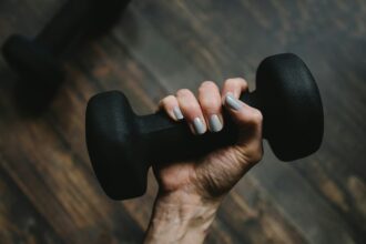 Person holding a dumbbell amid calls by IT professionals for stronger AI regulation, according to SolarWinds research.