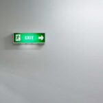 shutterstock 234875881 green fire exit sign against an indistinct soft white background