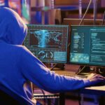 Hooded spy in underground hideout trying to steal valuable data by targeting governmental websites with weak security. Espionage specialist doing cyber attacks to gain access to sensitive info