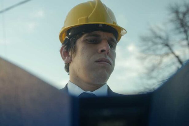 Beardless Construction Engineer or Contractor in a Helmet and Suit Examining Blueprints in a Blue Folder and Getting Frustrated over a Faulty Detail