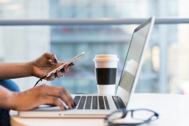 Photo of a person using their mobile smartphone while at a computer to illustrate the launch of OpenAI Operator that promises to democratise agentic AI by bringing agents into the browser.