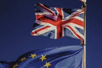 Flag of the UK flying above that of the EU as a techUK report warns the government must act to maintain semiconductor industry leadership to deliver economic growth, support its wider industrial strategy, and match global investments like the European Chips Act.