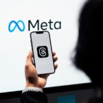 Person holding a phone displaying the Threads social media platform in front of the Meta logo as the company confirms plans to utilise content shared by its adult users in the EU (European Union) on platforms like Instagram and Facebook to train its AI models.