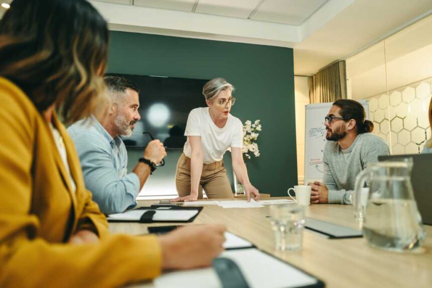 Mature businesswoman leading a discussion with her team in a boardroom. Group of creative businesspeople sharing ideas during a meeting in a modern workplace.