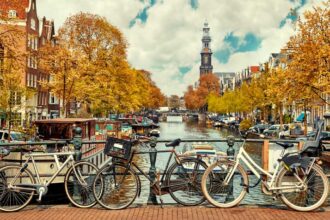 Bike over canal Amsterdam city. Picturesque town landscape in Netherlands with view on river Amstel.