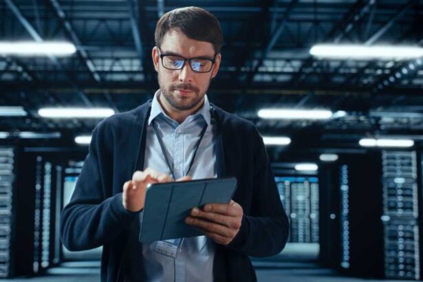Male IT Specialist Walks Between Row of Operational Server Racks in Data Center. Engineer Uses Tablet Computer for Maintenance. Concept for Cloud Computing, Artificial Intelligence, Cybersecurity.