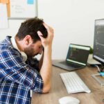 Stressed upset programmer having problems developing new software and looking worried because of the coding of an app