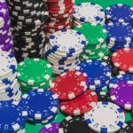 stacks of red white blue green black purple casino chips or betting chips on green gambling or gaming table