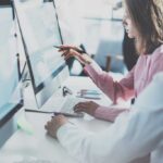 Coworkers team in modern office.Project managers work new idea.Young business crew working with startup studio.Desktop computer table,showing presentation,reflection monitor.Blurred,film effect.