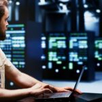 System administrator typing supercomputer hub disaster recovery plan on laptop to provide fast restoration of service, limiting damage and minimizing interruptions to normal operations