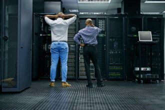 Meanwhile in the server room.... Rearview shot of two IT technicians having difficulty repairing a computer in a data center.