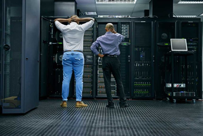 Meanwhile in the server room.... Rearview shot of two IT technicians having difficulty repairing a computer in a data center.