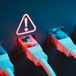 A photograph of a row of Ethernet cables plugged into ports, with a warning sign illuminated above one of the ports.