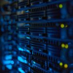 Server racks with illuminated indicators in a dimly lit data center.